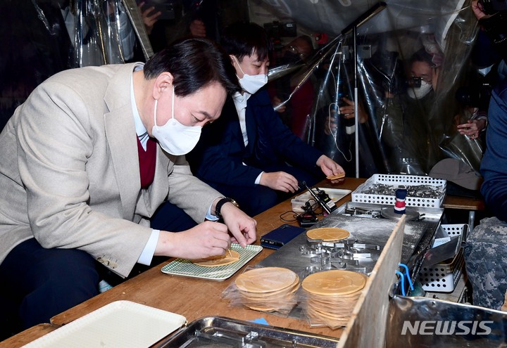 [서울=뉴시스] 국회사진기자단 = 윤석열 국민의힘 대선 후보와 이준석 대표가 8일 서울 종로구 대학로에서 거리인사 중 달고나 뽑기 체험을 하고 있다. 2021.12.08. photo@newsis.com