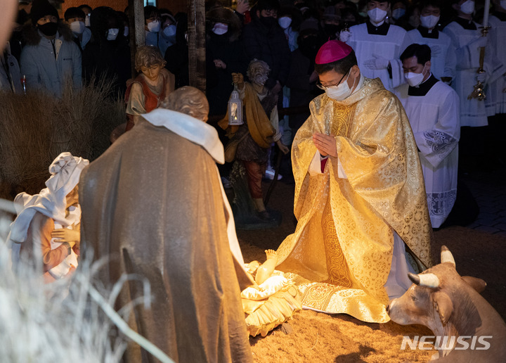 [서울=뉴시스] 정병혁 기자 = 정순택 서울대교구장 대주교가 25일 서울 명동성당 앞마당에서 아기 예수를 말구유에 안치하는 구유 예절의식을 하고 있다. (공동취재사진) 2021.12.25. photo@newsis.com