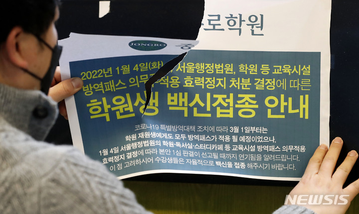 [서울=뉴시스] 홍효식 기자 = 법원이 코로나19 방역패스의 효력을 일부 정지한 14일 서울 마포구 종로학원 강북본원에서 관계자가 백신접종 안내문을 떼고 있다. 이번 결정으로 12~18세 청소년에 대한 서울시 17종 시설 전부에서 방역패스의 효력이 모두 정지된다. 2022.01.14. yesphoto@newsis.com