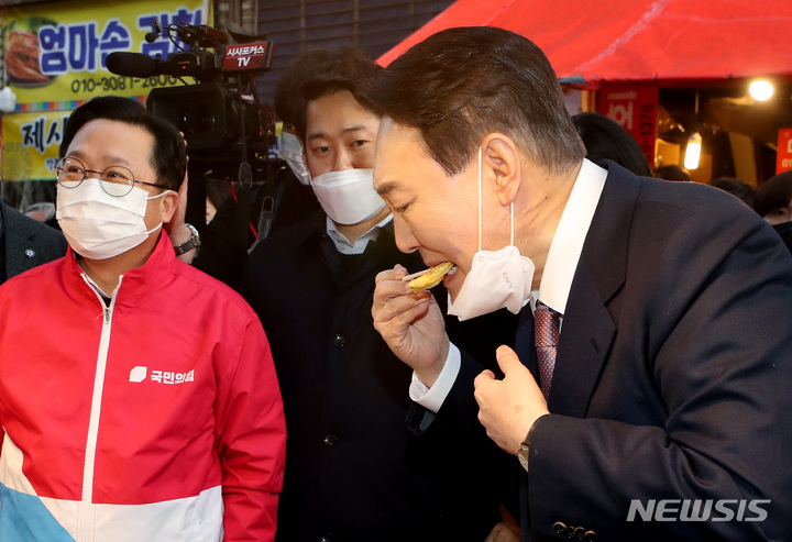 [대전=뉴시스] 전신 기자 = 윤석열 국민의힘 대선 후보가 21일 대전 동구 중앙시장을 방문해 전을 시식하고 있다. 2022.01.21. photo1006@newsis.com