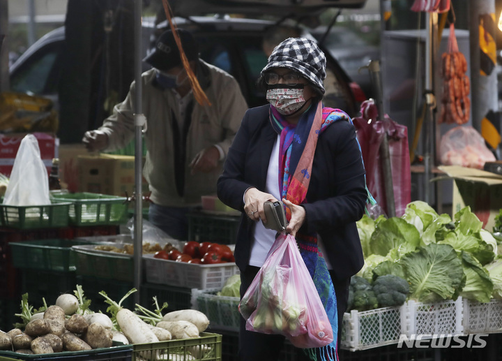 [타이베이=AP/뉴시스] 대만 수도 타이베이에 있는 채소가게에서 22일 코로나19 예방을 위해 마스크를 착용한 손님이 청경채 등을 사고 있다. 2022.02.24 