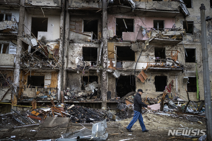 [키예프=AP/뉴시스] 25일(현지시간) 우크라이나 키예프에서 주민들이 러시아의 로켓 공격으로 파손된 건물 앞을 지나고 있다. 2022.02.25.