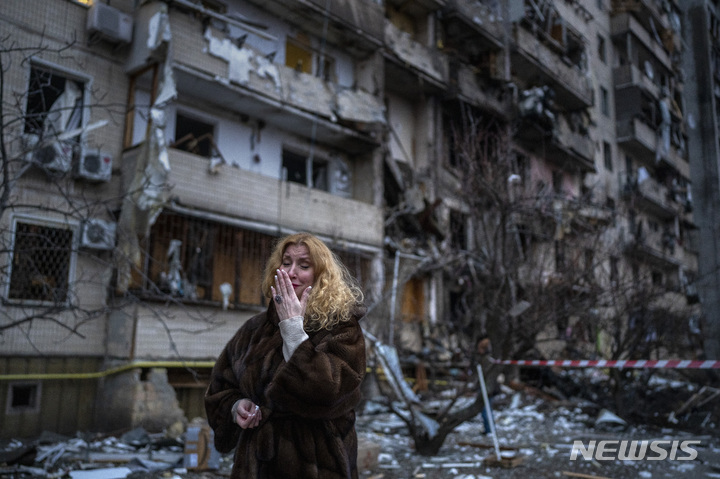 [키예프=AP/뉴시스] 25일(현지시간) 우크라이나 키예프에서 한 여성이 러시아의 로켓 공격으로 파손된 자신의 집 근처에 서서 흐느끼고 있다. 2022.02.25.