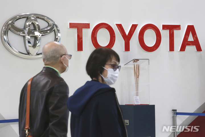 [도쿄=AP/뉴시스]지난 2021년 10월18일 일본 도쿄의 한 전시장에 걸린 도요타자동차 로고 앞으로 마스크를 착용한 시민들이 지나가고 잇다. 2023.01.17.