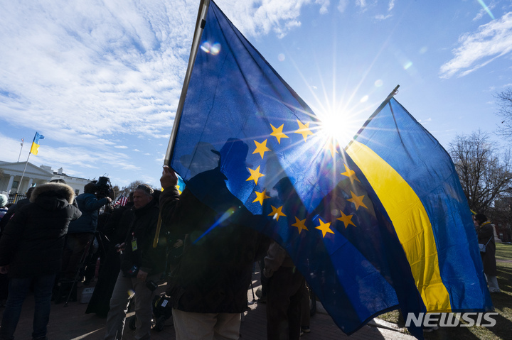 [워싱턴=AP/뉴시스] 13일 워싱턴 백악관 근처 라파예트 공원에서 운동가들이 러시아의 우크라이나 전쟁에 항의하며 광대한 밀밭가 푸른하늘을 담은 우크라이나 깃발을 들고 있다. 2022.03.13. *재판매 및 DB 금지