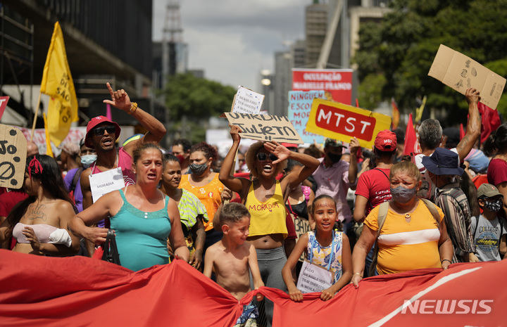 [상파울루=AP/뉴시스] 17일(현지시간) 브라질 상파울루에서 어린이를 포함한 시위대가 손팻말 등을 들고 퇴거 유예 시한 연장을 요구하는 구호를 외치고 있다. 브라질 대법원이 코로나19 대유행 동안 불법 거주자에 부과했던 퇴거 유예 시한이 3월 말로 다가오면서 시위대는 이의 연장을 요구하며 시위를 벌였다. 2022.03.18