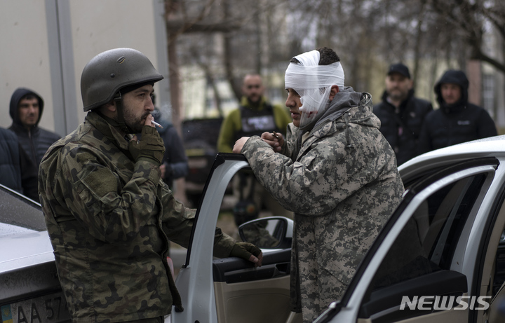 [이르핀=AP/뉴시스] 30일(현지시간) 우크라이나 키이우 외곽 이르핀에서 대피한 부상자가 우크라이나 군인과 얘기를 나누고 있다. 2022.03.31.