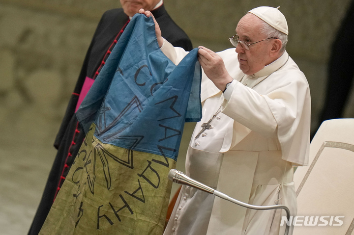 [바티칸=AP/뉴시스] 프란치스코 교황이 지난달 6일(현지시간) 바티칸 바오로 6세 홀에서 우크라이나 북부 부차에서 보내온 우크라이나 국기를 들어 보이고 있다. 2022.05.18.