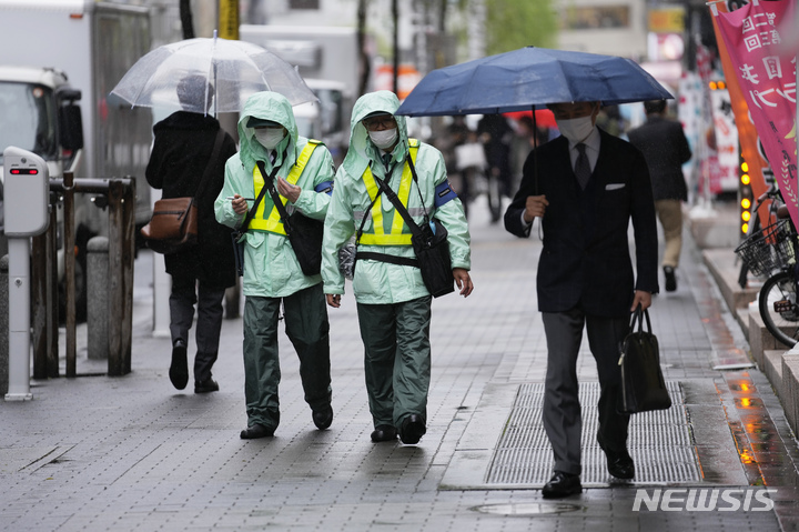 [도쿄=AP/뉴시스] 일본 수도 도쿄 시내에서 15일 코로나19 예방을 위해 마스크를 착용한 주차단속 요원들이 정차 위반한 차량을 살피고 있다. 2022.04.17 