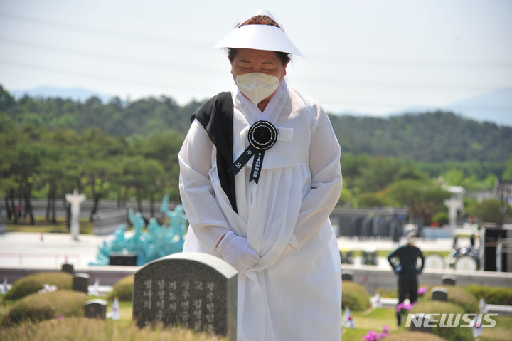 [광주=뉴시스] 이영주 기자 = 제42주년 5·18민주화운동 기념식 하루를 앞둔 17일 오전 광주 북구 운정동 국립5·18민주묘지에서 고 김영철 열사의 아내 김순자(70) 여사가 묵념하고 있다. 2022.05.17 leeyj2578@newsis.com