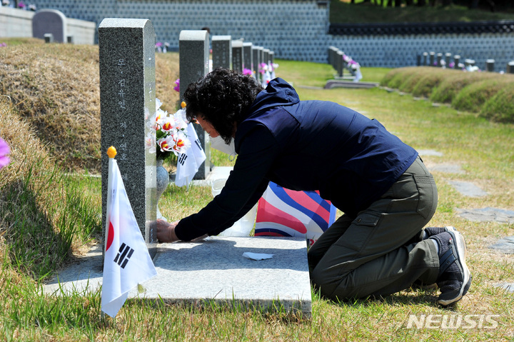 [광주=뉴시스] 이영주 기자 = 제42주년 5·18민주화운동 기념식 하루를 앞둔 17일 오전 광주 북구 운정동 국립5·18민주묘지에서 고 윤승봉 열사의 동생 윤연숙(68) 씨가 묘비를 닦고 있다. 2022.05.17 leeyj2578@newsis.com