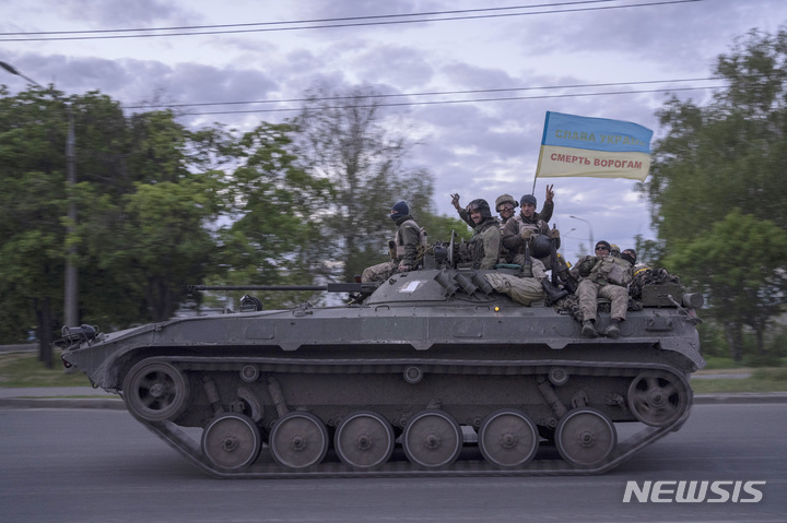 [하르키우=AP/뉴시스] 16일(현지시간) 우크라이나 동부 하르키우에서 우크라이나 군인들이 "우크라이나에 영광을" "적에게 죽음을"이라고 쓰인 깃발을 단 전차에 올라 손을 흔들며 도로를 지나고 있다. 2022.05.17. 