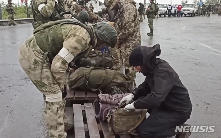 [마리우폴=AP/뉴시스] 19일(현지시간) 우크라이나 동부 도네츠크인민공화국(DPR) 산하 마리우폴에서 러시아 군인들이 아조우스탈 제철소에서 나온 우크라이나 군인들의 짐을 검사하고 있다. 2022.05.20.