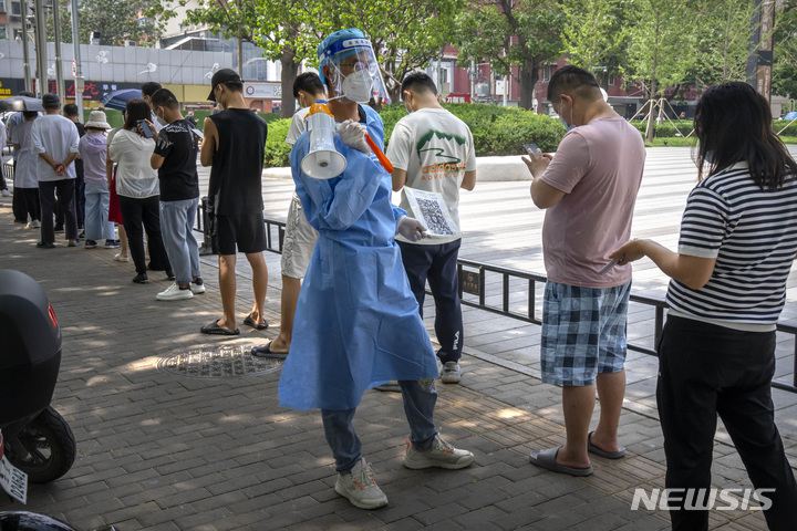 [베이징=AP/뉴시스] 15일 중국 베이징의 차오양구의 코로나19 집단 검사소에서 보호복을 입은 한 근로자가 줄 선 시민들에게 QR 코드를 보여주고 있다. 2022.06.15