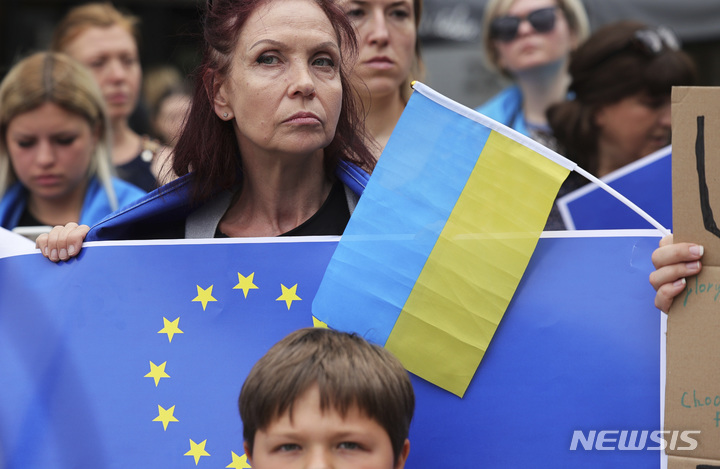 [브뤼셀=AP/뉴시스] 23일(현지시간) 벨기에 브뤼셀에서 EU 정상회의가 열린 가운데 시위대가 우크라이나 EU 가입 후보국 지위 지지 시위를 하고 있다. 이날 회의에 참석한 27개 EU 회원국 정상은 우크라이나와 몰도바에 대한 EU 가입 후보국 지위를 부여하기로 합의했다. 2022.06.24.
