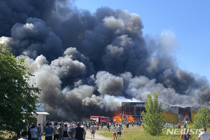 [크레멘추크=AP/뉴시스] 27일(현지시간) 우크라이나 크레멘추크에서 시민들이 러시아의 미사일 공격으로 연기가 솟구치는 쇼핑몰을 지켜보고 있다. 우크라이나 당국은 이번 공격으로 최소 13명이 숨지고 58명이 다쳤다고 밝혔다. 2022.06.28.