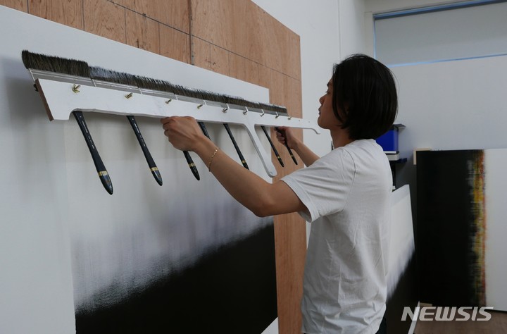 [서울=뉴시스]김수수 작가가 직접 제작한 2m 길이의 붓으로 한번에 작업하는 장면. 