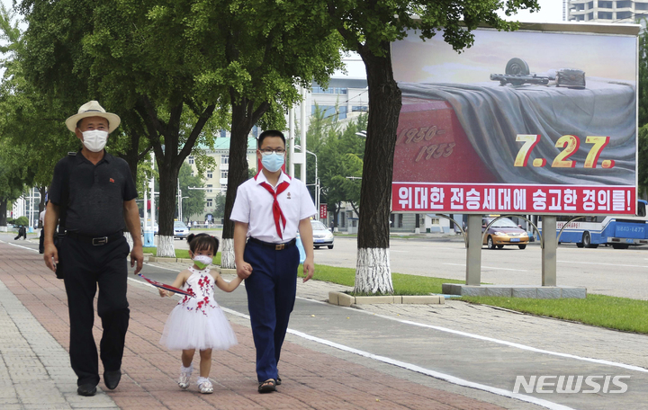 [평양=AP/뉴시스] 6·25 한국전쟁 정전 69주년인 27일 북한 평양의 승리 거리에서 주민들이 전승을 경축하는 포스터 앞을 지나고 있다. 북한은 6·25 한국전쟁 정전 체결을 미군에 승리했다고 주장하며 '조국 해방전쟁 승리의 날'로 기념한다. 2022.07.28.