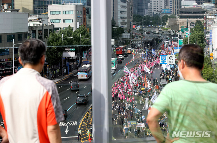 [서울=뉴시스] 조수정 기자 = 13일 오후 서울 중구 숭례문 앞에서 열린 8·15 전국노동자대회 및 자주평화통일대회 참가자들이 세종대로에서 출발, 용산 대통령실을 향해 행진하는 모습을 시민들이 지켜보고 있다. 2022.08.13. chocrystal@newsis.com