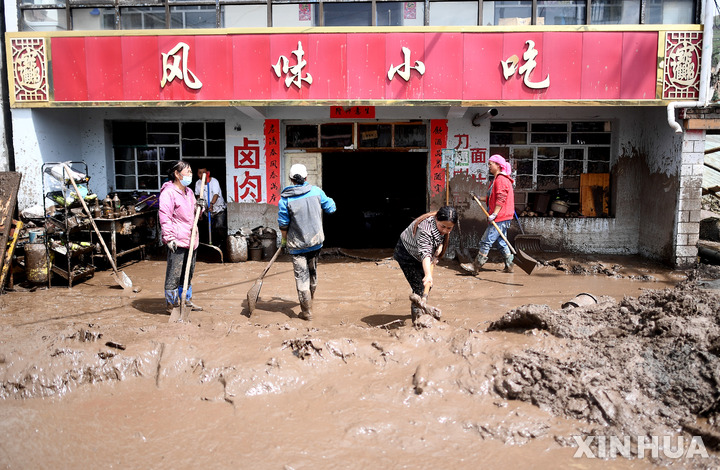 [다퉁(중국 칭하이성)=신화/뉴시스]중국 서부 칭하이(靑海)성 다퉁현에서 18일 주민들이 17일 밤 폭우로 발생한 산사태로 흘러내린 토사를 치우고 있다. 산사태로 강 줄기가 바뀌며 인구 밀집 지역에서 급작스레 홍수가 발생해 최소 16명이 숨지고 18명이 실종됐다고 중국 관영 언론이 18일 보도했다. 2022.8.18