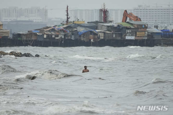 [마닐라=AP/뉴시스]25일 필리핀 수도 마닐라 톤도의 해변 슬럼가에 태풍 노루가 접근하면서 한 주민이 강한 파도를 따라 수영하고 있다. 2022.09.26.