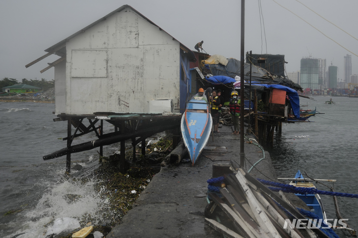 [마닐라=AP/뉴시스]25일 필리핀 마닐라에 태풍 노루가 접근하는 동안 한 주민이 톤도의 해변 슬럼가에서 자신의 집 지붕을 수리하고 있다. 2022.09.26.