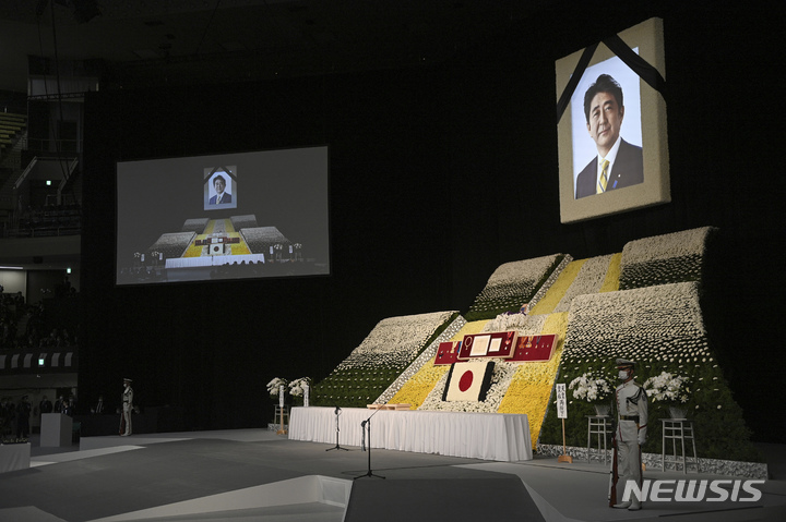 [도쿄=AP/뉴시스] 아베 신조 전 일본 총리의 영정 사진이 지난 27일 도쿄의 니혼부도칸 앞 쪽에 마련된 제단 위에 놓여 있다. 제단 앞쪽에는 헌화대가 마련돼 있다.2022.09.28.