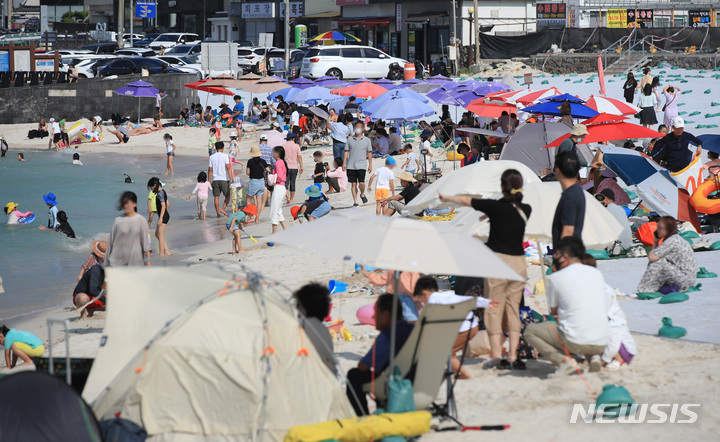 [제주=뉴시스] 우장호 기자 = 낮 최고기온이 30도에 육박하는 무더운 날씨를 보인 3일 오후 제주시 한림읍 협재해수욕장을 찾은 관광객들이 바닷바람을 맞으며 더위를 식히고 있다. 2022.10.03. woo1223@newsis.com