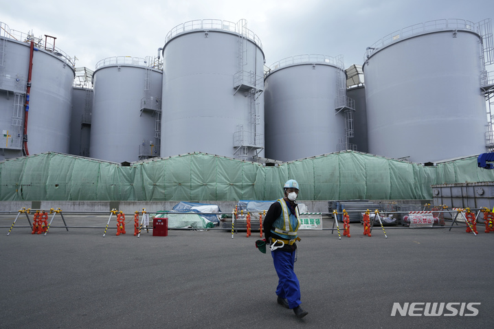 [후쿠시마=AP/뉴시스]지난 3월3일 도쿄전력이 운영하는 일본 후쿠시마현 후쿠시마 제1 원자력발전소의 오염수 보관 탱크 앞을 한 근로자가 지나가고 있다. 2022.11.10.