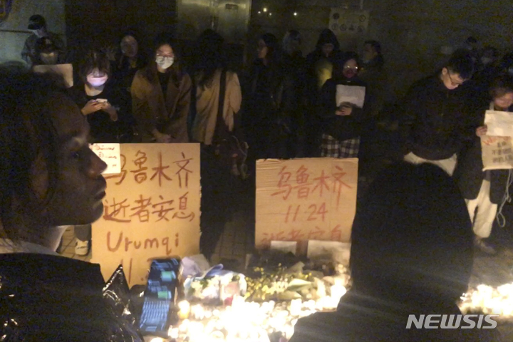 [상하이(중국)=AP/뉴시스] 11월 26일 밤 (현지시간) 중국 상하이 시내의 코로나19봉쇄 반대 시위대가 중국 신장의 한 아파트 화재로 숨진 10명의 영혼을 위로하는 집회를 갖고 있다.  