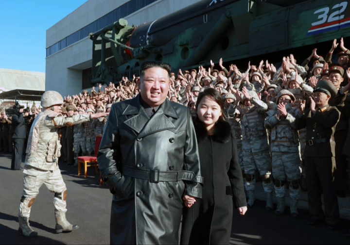 [서울=뉴시스] 북한 조선중앙TV가 27일 북한 김정은 국무위원장이 신형대륙간탄도미사일 화성포-17형 시험발사 참여했던 공로자들과 함께 기념사진을 찍고 그들의 노력을 평가했다고 보도했다. 이날 김 국무위원장은 둘째 딸을 데리고 나와 과시하는 모습을 보였다. 이날 공개된 사진에서 털이 달린 검은색 긴 코트를 입은 둘째 딸은 가죽 롱코트 차림의 김 위원장의 팔짱을 끼며 나란히 걷는가 하면, '화성-17형' 발사 공로자들에게 박수를 보내는 등 자연스러운 모습을 연출했다. (사진=조선중앙TV 캡쳐) 2022.11.27. photo@newsis.com *재판매 및 DB 금지