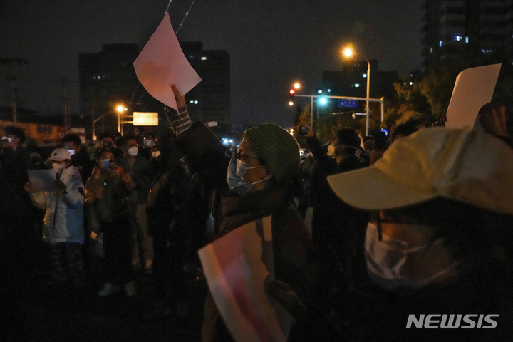 [베이징=AP/뉴시스] 27일 중국 베이징에서 코로나19 봉쇄 정책에 항의하는 시위대가 '백지'를 들고 구호를 외치고 있다. 시민들은 정부에 항의하는 의미를 담은 ‘백지’를 들고 28일 새벽까지 시위를 이어갔다. 2022.11.28.