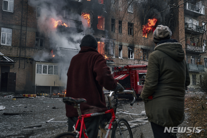 [바흐무트=AP/뉴시스] 7일(현지시간) 우크라이나 도네츠크주 바흐무트에서 주민들이 러시아군의 포격으로 불타는 그들의 아파트를 바라보고 있다. 2022.12.08.
