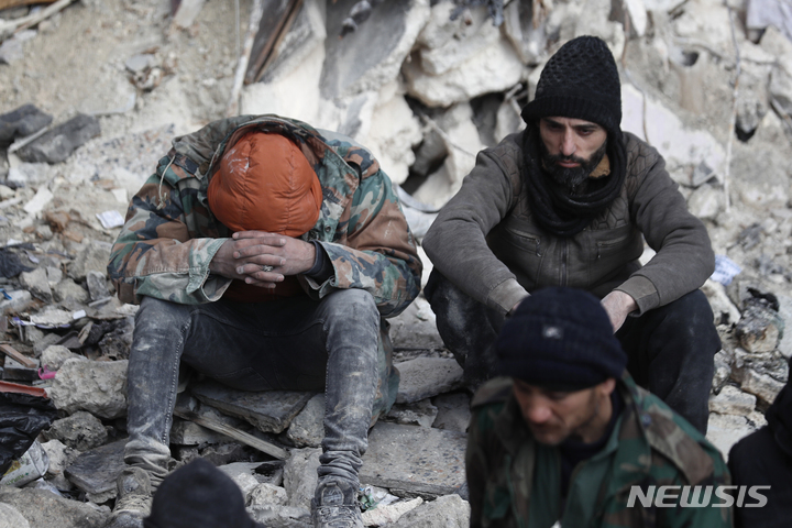[알레포=AP/뉴시스] 7일(현지시간) 시리아 알레포에서 주민들이 지진으로 무너진 건물 잔해에 암울한 표정으로 앉아 있다. 튀르키예와 시리아를 강타한 지진으로 지금까지 사망자가 7800명을 넘었다. 2023.02.08. 
