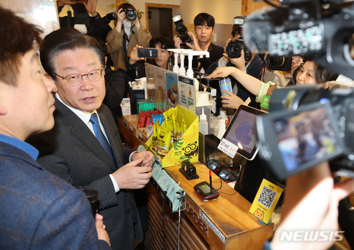 [서울=뉴시스] 권창회 기자 = 이재명 더불어민주당 대표가 서울 성북구 장위2동 카페에서 지역사랑상품권을 이용해 커피를 구입하고 있다.(공동취재사진) 2023.03.23.photo@newsis.com