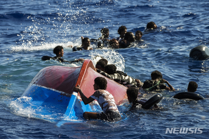 [람페두사( 이탈리아)=AP/뉴시스] 난파된 배의 파편을 잡고 람페두사 섬 인근 해상에서 구조를 기다리는 난민들. 2023. 08.10. 