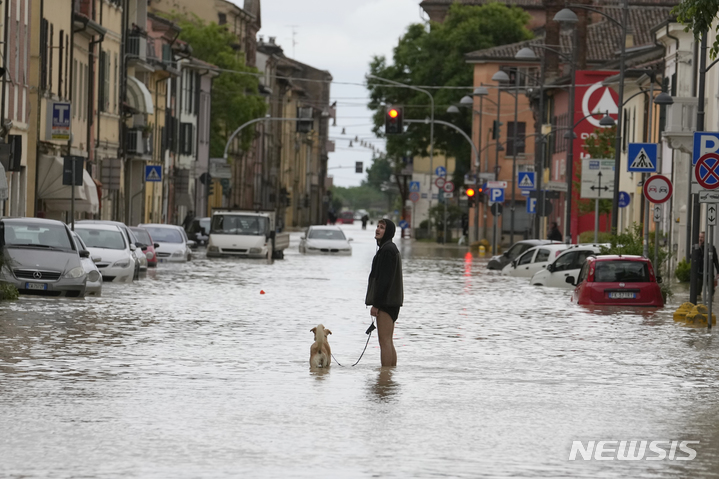 [카스텔 볼로네제=AP/뉴시스] 17일(현지시각) 이탈리아 에밀리아-로마냐주 카스텔 볼로네제 마을에서 한 남성이 반려견과 침수 거리를 걷고 있다. 가뭄이 이어지던 이탈리아 북부에 폭우가 내리면서 홍수가 발생, 최소 8명이 숨지고 주민 수천 명이 대피했다. 2023.05.18.