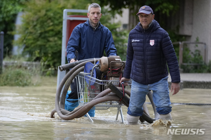 [카스텔 볼로네제=AP/뉴시스] 17일(현지시각) 이탈리아 에밀리아-로마냐주 카스텔 볼로네제 마을에서 주민들이 물을 퍼내기 위해 양수기를 옮기고 있다. 가뭄이 이어지던 이탈리아 북부에 내린 폭우가 내리면서 홍수가 발생, 최소 8명이 숨지고 주민 수천 명이 대피했다. 2023.05.18.