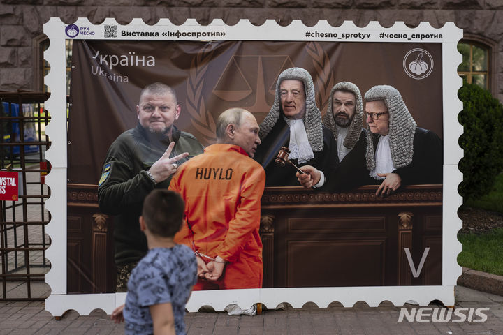 [키이우=AP/뉴시스] 3일(현지시각) 우크라이나 키이우에서 한 소년이 죄수복을 입은 블라디미르 푸틴 러시아 대통령이 법정에 선 것을 묘사한 전시물을 바라보고 있다. 2023.07.04.