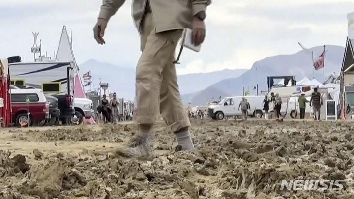 [블랙록( 미 네바다주)=AP/뉴시스] 갑작스런 폭우로 진흙탕 속에 고립되었던 미국 네바다 사막의 '버닝 맨' 축제 참가자들이 비가 갠 4일엔 진흙 속을 걸어서 이동하고 있다. 2023.09.06. 