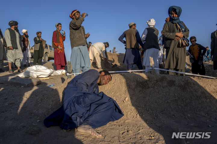 [제데흐잔=AP/뉴시스] 9일(현지시각) 아프가니스탄 헤라트주 제데흐잔에서 한 남성이 지진으로 숨진 아내의 무덤에 누워 아내의 죽음을 애도하고 있다. 지난 7일 아프간에서 발생한 지진으로 지금까지 최소 2400명이 숨지고 2천 명이 다친 것으로 알려졌다. 2023.10.10.