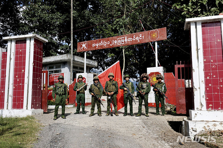 [쿤룽=AP/뉴시스] 지난 12일(현지시각) 미얀마민족민주동맹군(MNDAA) 소속 무장대원들이 샨주 쿤룽에 있는 미얀마 보병대대를 점령한 후 부대 앞에서 MNDAA 깃발을 들고 기념 촬영하고 있다. MNDAA는 소수민족 군대인 아라칸군(AA), 타앙민족해방군(TNLA)과 '형제 동맹'을 맺고 지난달 말부터 샨주에서 군부 독재 타도를 목표로 미얀마군과 교전을 벌이고 있다. '형제 동맹'은 전국적으로 공세를 확대할 것이라고 밝혔다. 2023.11.14.