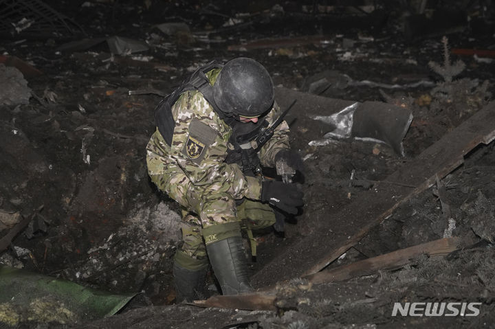 [하르키우=AP/뉴시스] 1월23일(현지시각) 우크라이나 하르키우에서 우크라이나 공병대원이 러시아 로켓 공격으로 건물 부근에 생겨난 포탄 구덩이를 조사하고 있다. 올레흐 시네후보우 하르키우 주지사는 러시아 공습으로 최소 6명이 숨지고 미성년자 4명 포함, 48명이 다쳤다고 밝혔다. 2024.01.24.