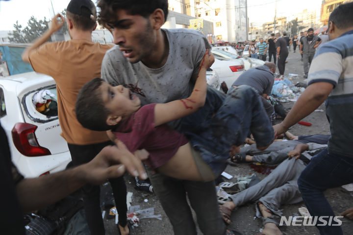 [가자시티=AP/뉴시스] 지난해 11월3일 가자지구 북부 가자시티의 알시파 병원 입구 밖에서 한 남성이 이스라엘군 공습으로 다친 어린이를 안고 이송하는 모습. 2024.03.29.