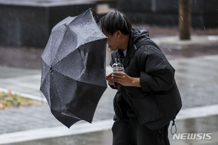 [서울=뉴시스] 정병혁 기자 = 25일 서울 종로구 광화문광장에서 우산을 쓴 시민들이 비바람을 맞으며 이동하고 있다. 2024.03.25. jhope@newsis.com