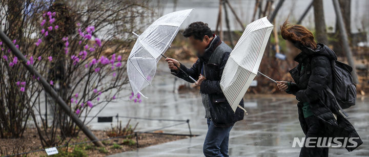 [서울=뉴시스] 정병혁 기자 = 25일 서울 종로구 광화문광장에서 우산을 쓴 시민들이 비바람을 맞으며 이동하고 있다. 2024.03.25. jhope@newsis.com