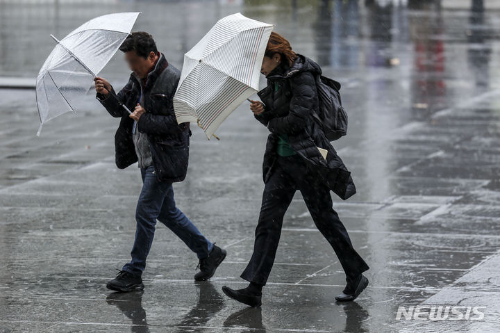 [서울=뉴시스] 정병혁 기자 = 지난 25일 서울 종로구 광화문광장에서 우산을 쓴 시민들이 비바람을 맞으며 이동하고 있다. 2024.03.25. jhope@newsis.com