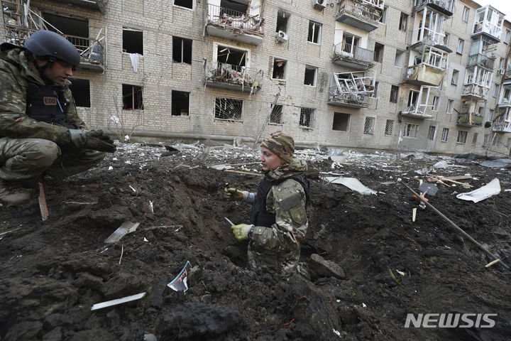 [하르키우=AP/뉴시스] 27일(현지시각) 우크라이나 하르키우에서 경찰관들이 러시아군의 포격으로 파손된 아파트 앞에 생긴 웅덩이를 조사하고 있다. 2024.03.28.