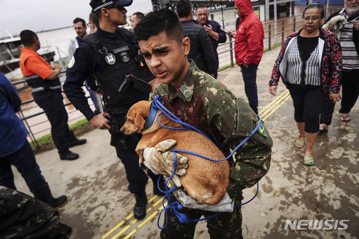 [리우그란데두술=AP/뉴시스] 3일(현지시각) 브라질 남부 리우그란데두술주 포르투 알레그레에서 한 군인이 폭우로 침수된 지역에서 강아지를 대피시키고 있다. 2024.05.07.