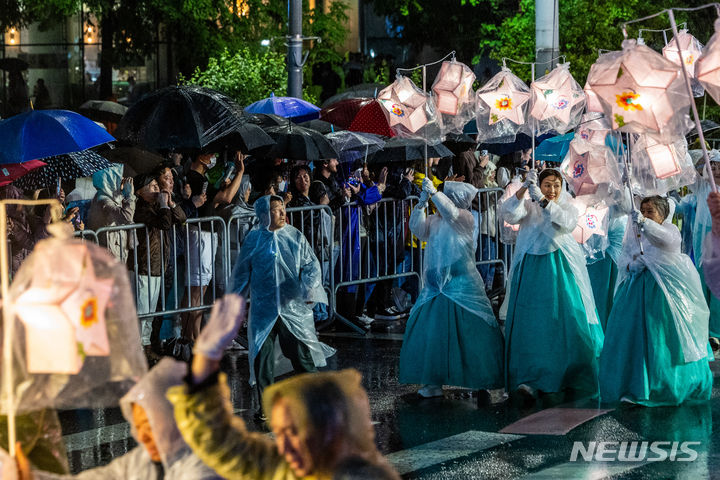 [서울=뉴시스] 김명년 기자 = 부처님오신날을 앞둔 11일 오후 서울 종로 일대에서 우산을 쓴 관람객들이 연등 행렬을 구경하고 있다. 2024.05.11. kmn@newsis.com